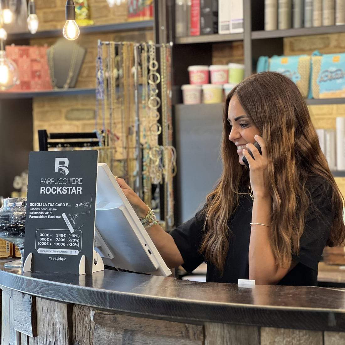 La receptionist di Parrucchiere Rockstar al telefono, al banco con le card VIP